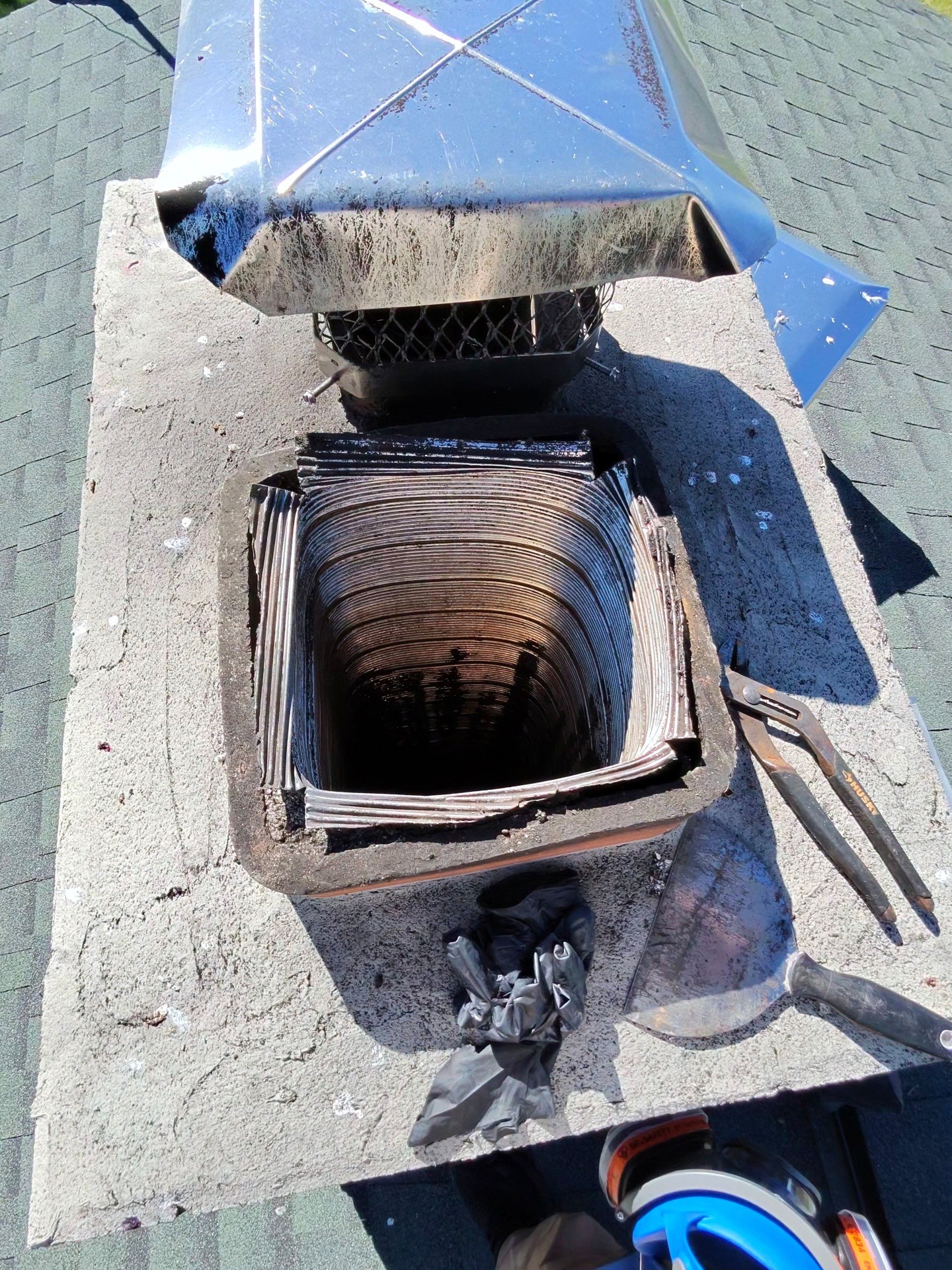 Open chimney flue with a removed cap and tools on the chimney crown