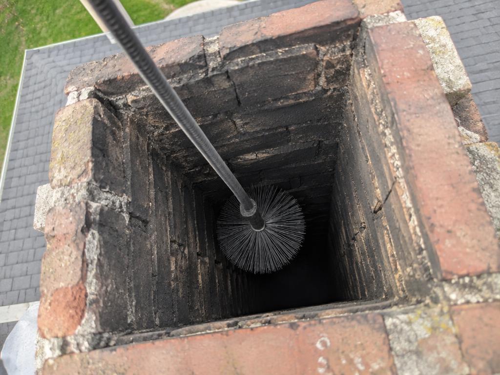 Wire chimney brush on flexible rods descending into a flue