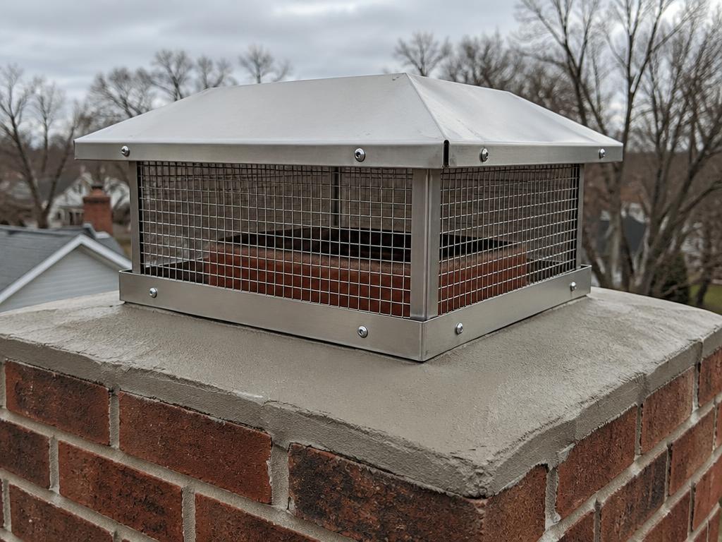 Stainless steel mesh chimney cap installed on a brick chimney